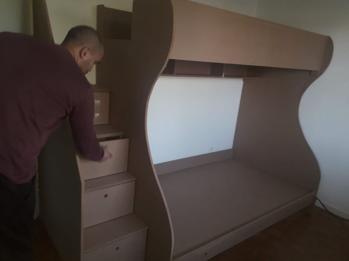 Work in progress: a man assembling a bespoke curved bunk unit with built-in step drawers.