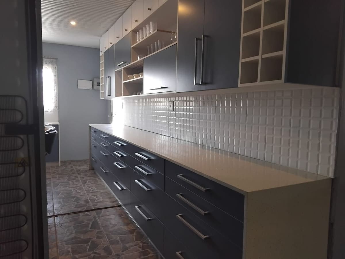 Long run of navy drawers under a white worktop and a white tiled splashback, with open shelving and a cube wine rack above.